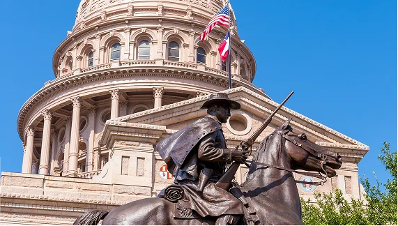 An equestrian statue stands before the Texas State Capitol, representing the state's elected officials and their leadership.