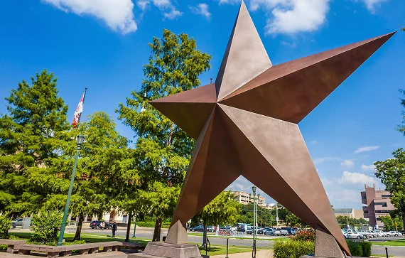 A large, rustic metal star sculpture stands outdoors, representing one of the many proud symbols of Texas culture.