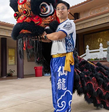 Kevin Glan in full, ornate costume, preparing for a traditional Lion Dance performance that connects community to rich history.