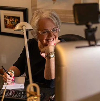 A smiling Marsha Hendler at her desk, embodying her role as a pioneering and successful business owner in the oil industry.