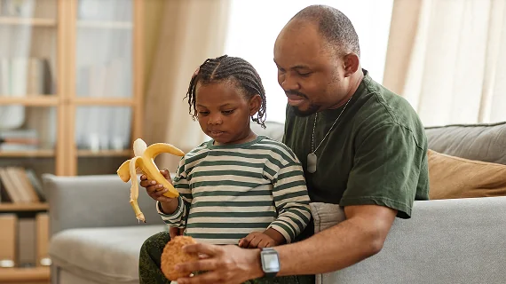 A father in a military-style shirt plays with his young child, illustrating the family support services available to military families.