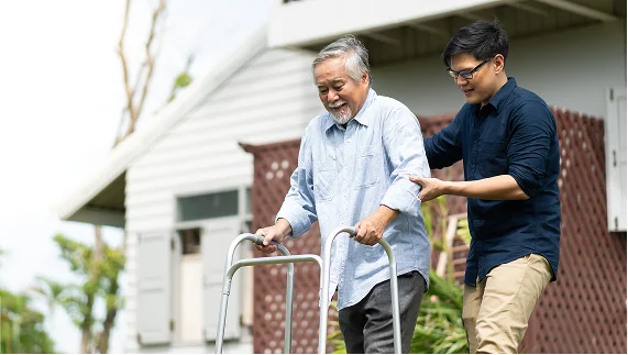 A caregiver assists a veteran using a walker up a set of stairs, illustrating the compassionate disability support available.
